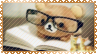 a stamp with a golden lace border. it shows a tedyd bear wearing glasses reading a book.